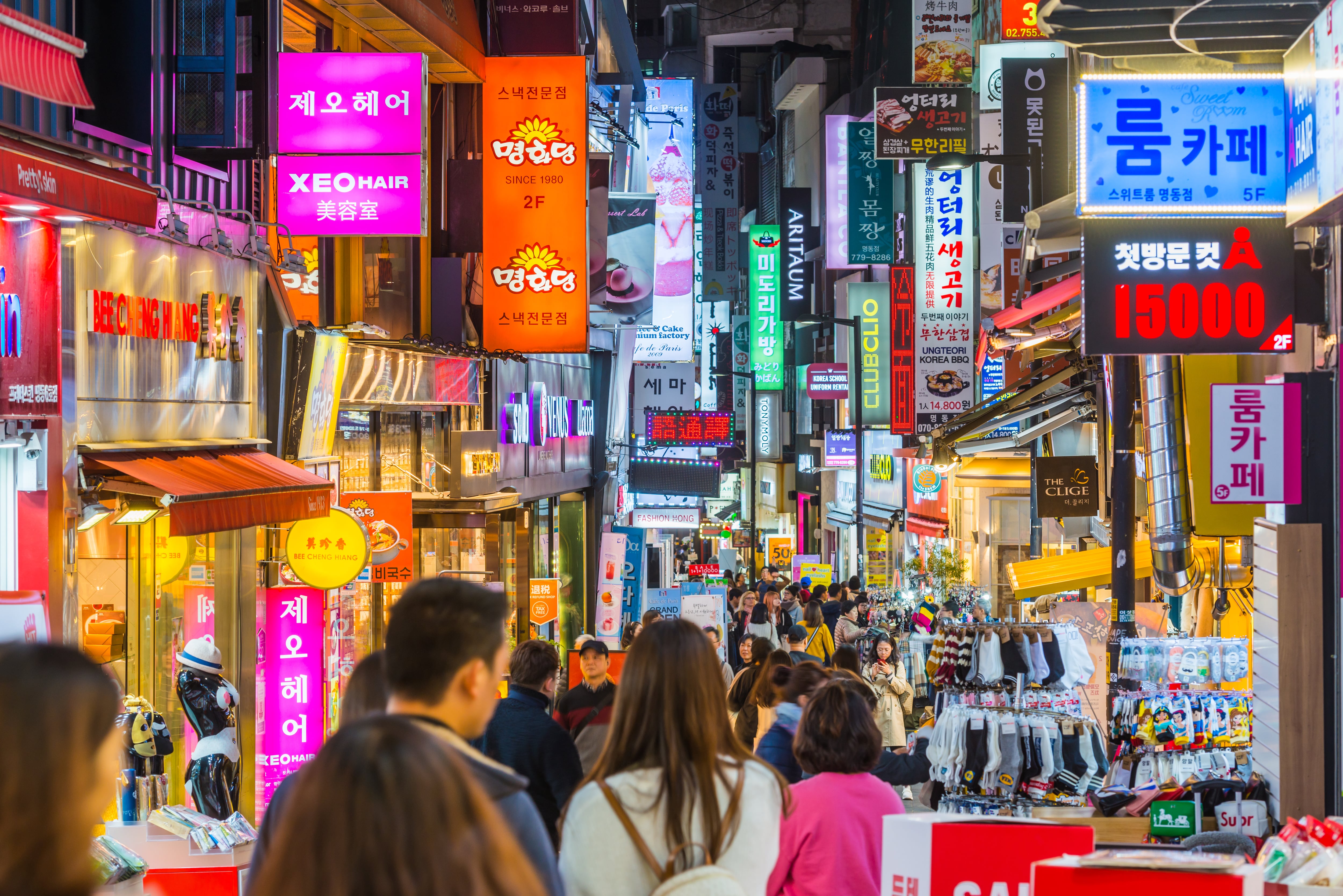 Crowds of shoppers along the pedestrianised streets of Myeong-dong overlooked by the neon lights of stores in the heart of Seoul at night, South Korea’s vibrant capital city.