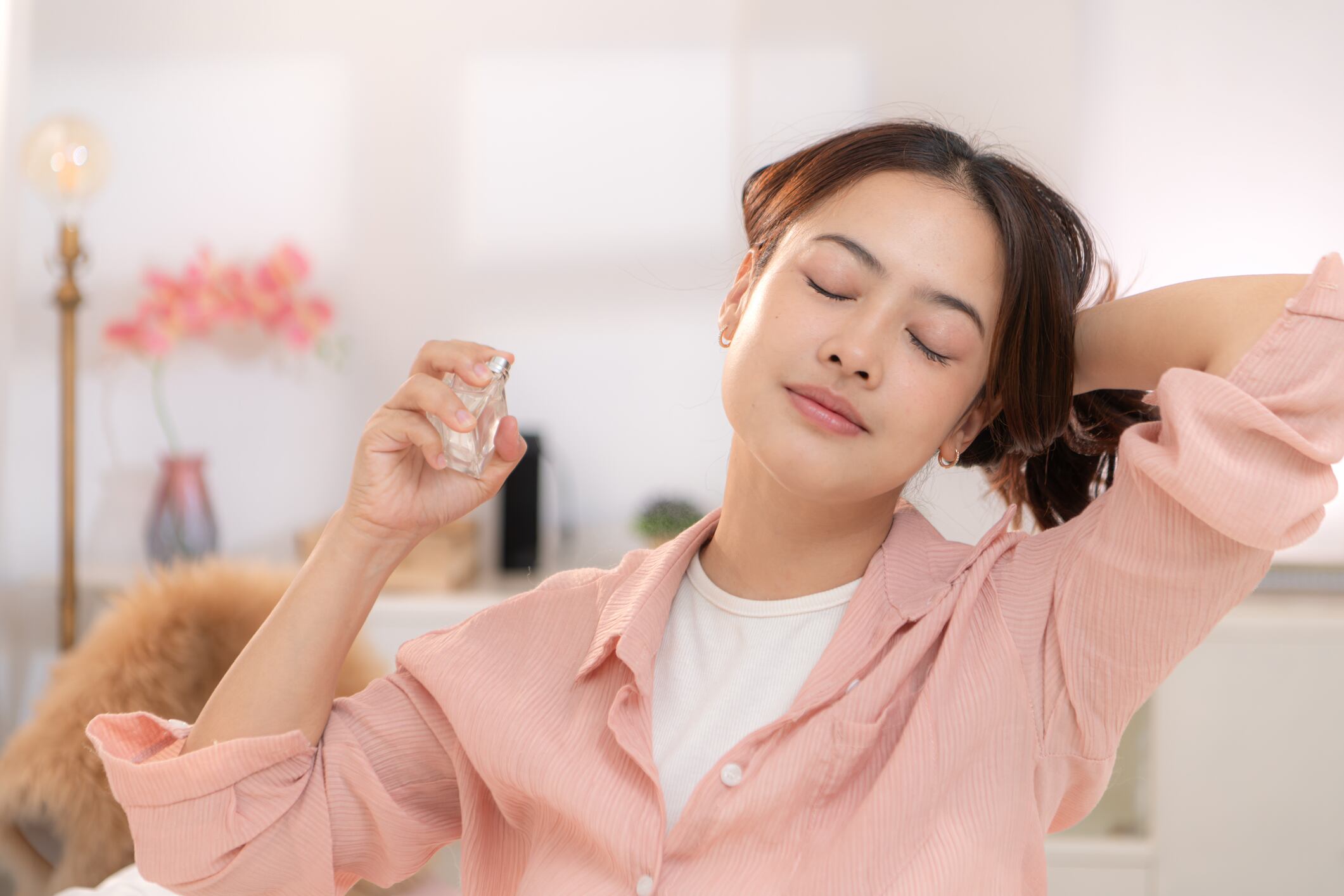 Asian young woman spraying perfume