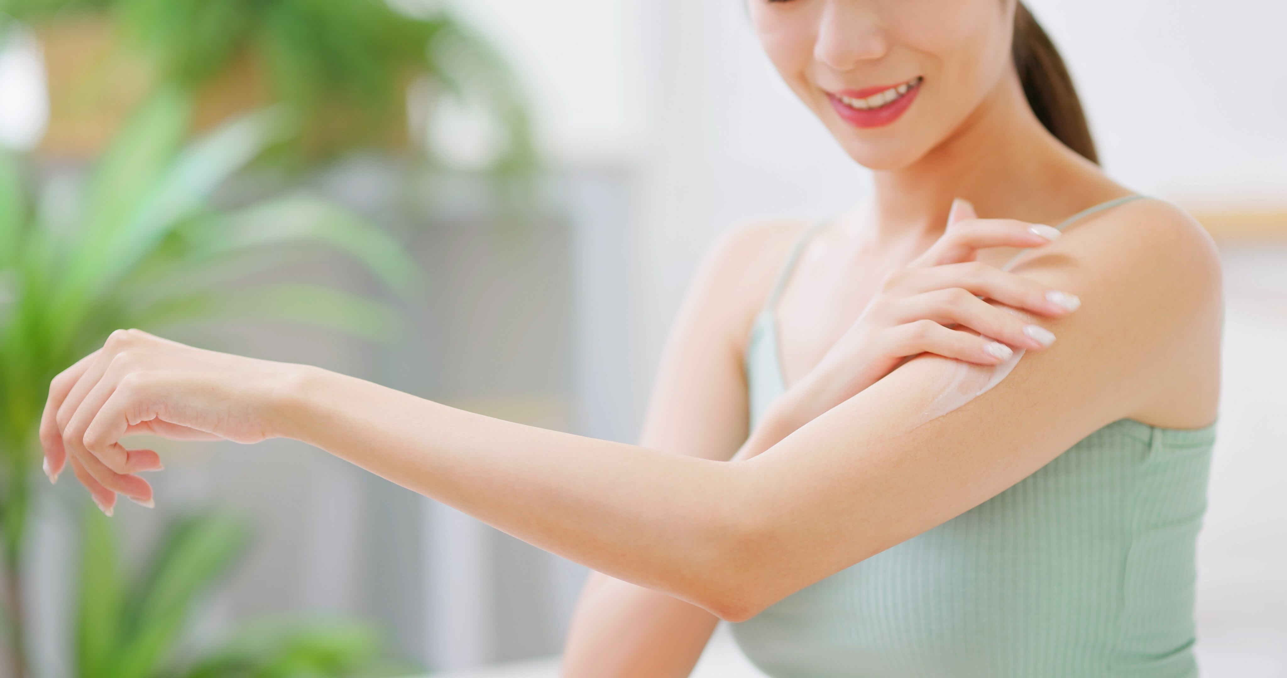 Asian woman applying skin care on arm