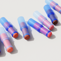 Translucent blue plastic blush-stick packages on a white background. These packages are made from plastic pulled out of the ocean by #tide ocean plastic and manufactured and distributed by Seacliff Beauty.